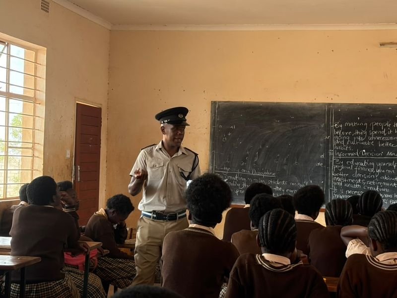 A uniformed officer addressing pupils in a classroom