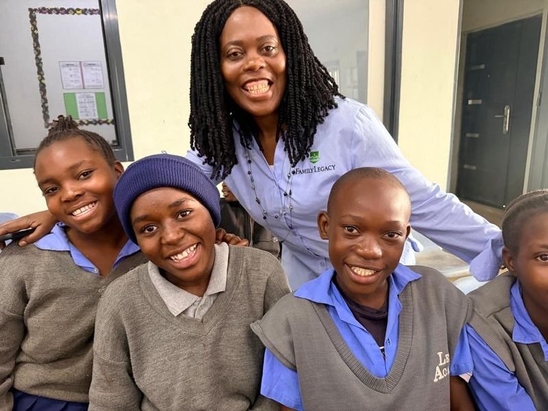 Pupils in school uniform gathered around a team member, smiling at the camera